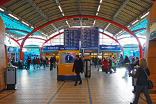 900037 Gezicht in de Stationshal van het Centraal Station te Utrecht, met op de achtergrond het grote vertrektijdenbord.